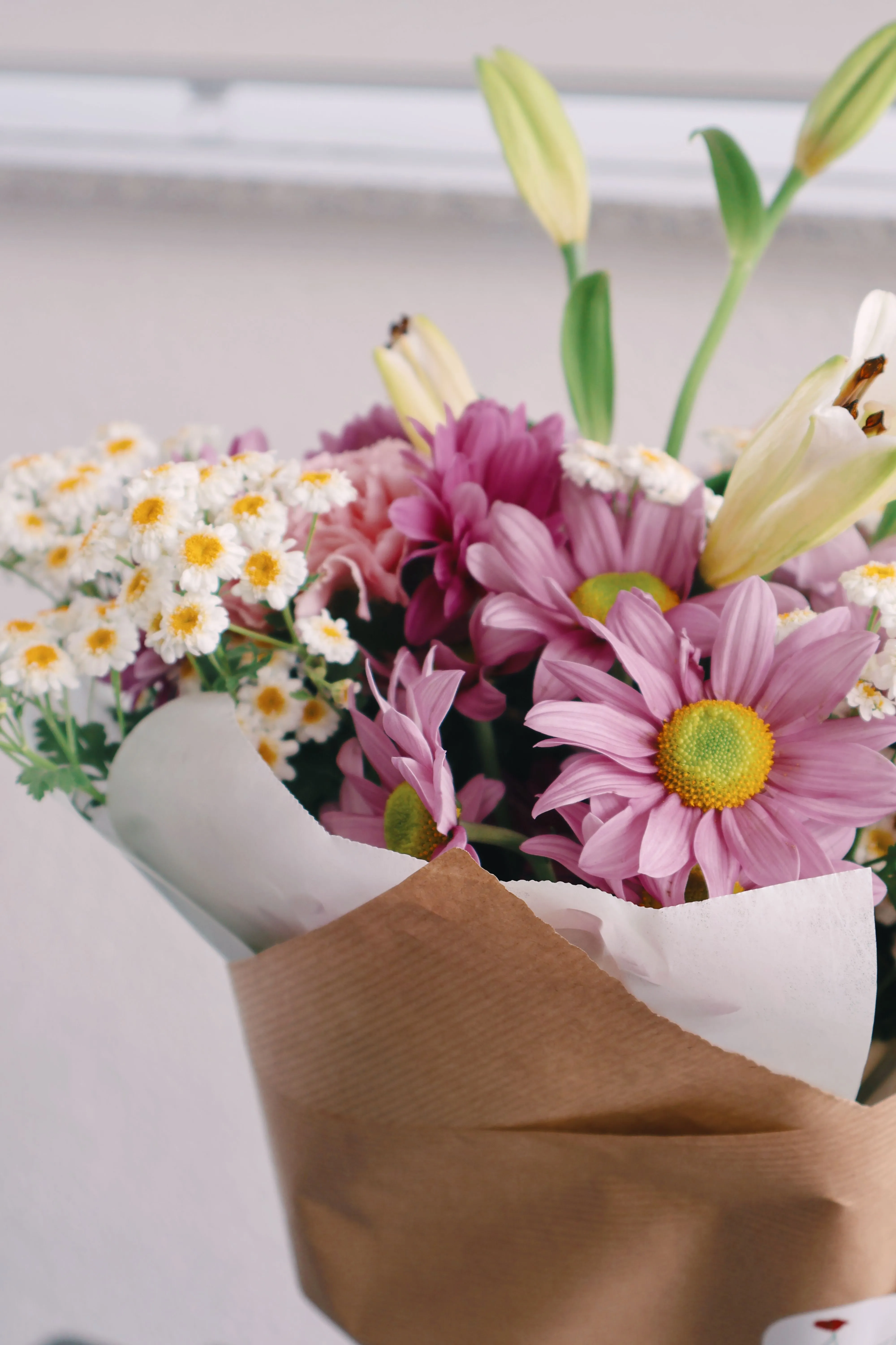 Ramo de flores rosadas, blancas y amarillas envuelto en papel
